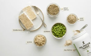 Plant-Based Athlete Nutrition: 7 Proven Strategies to Unlock Elite Performance 4 Top plant-based protein sources for athlete nutrition displayed on a white background, including blocks of tempeh, whole lentils, hemp seeds, edamame, quinoa, and a tub of pea protein powder.